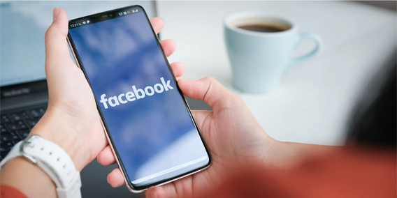 Woman looking at the facebook logo on her smartphone